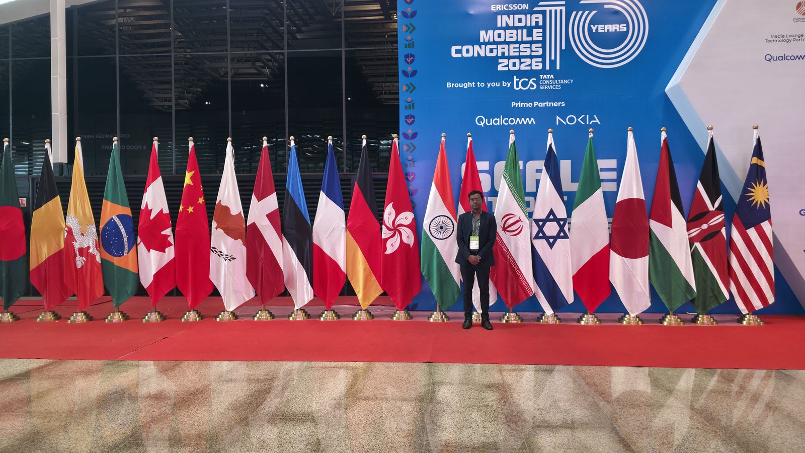 Team member with the flags at India Mobile Congress 2026.