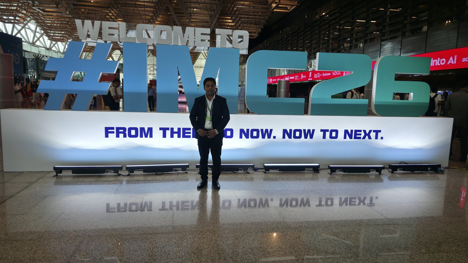 Team member in front of the IMC 2026 welcome sign.
